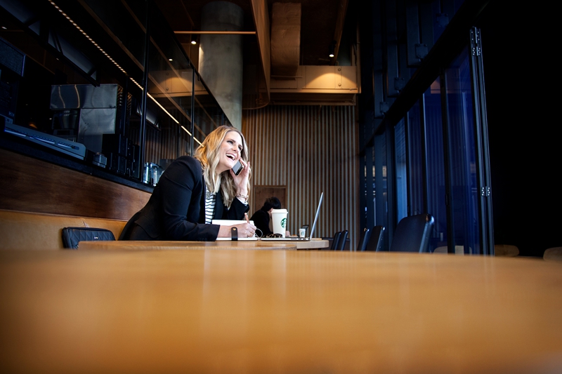 Female entrepreneur at a coffee shop talking on her phone.