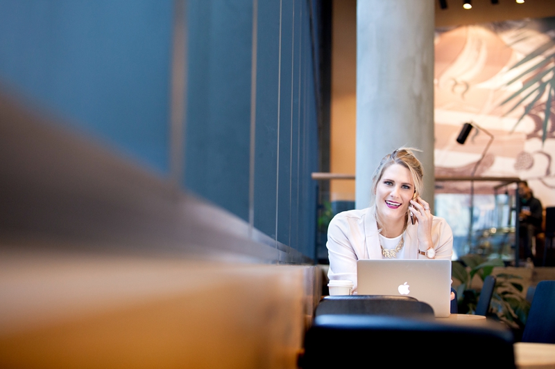 Business woman on the phone working on an Apple laptop sitting at Starbucks