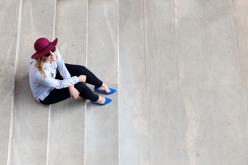 Pam Newman wearing blue shoes sitting on a staircase