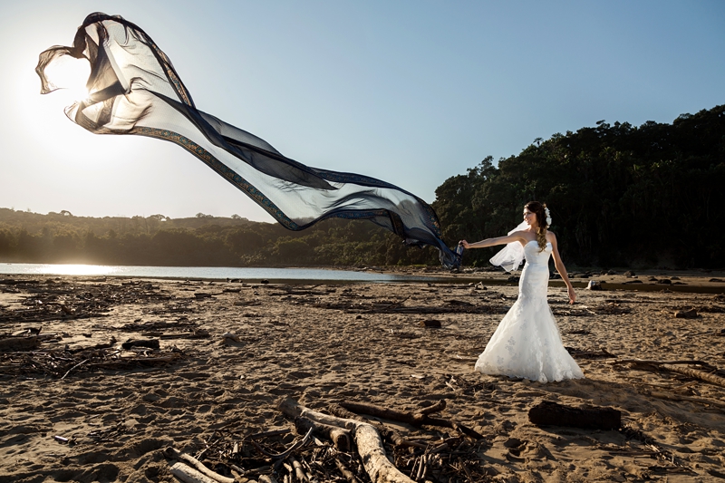 Bride waving blue fabric in the wind, on the beach, during afternoon light at the Estuary Hotel, Port Edward.