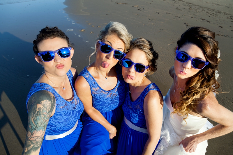 Bridesmaids pulling funny faces, wearing blue sunglasses, on the Beach at the Estuary Hotel, Port Edward