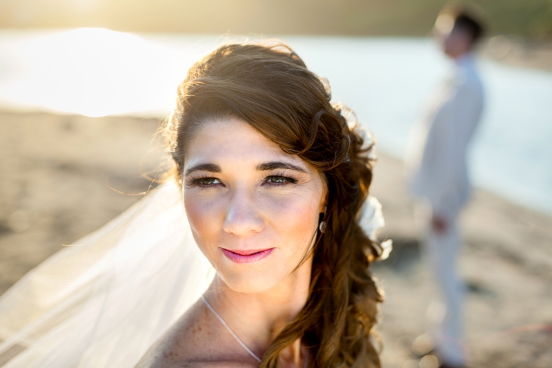 Brides veil flying in the wind, on the beach with the groom in the background during afternoon light at the Estuary Hotel, Port Edward.