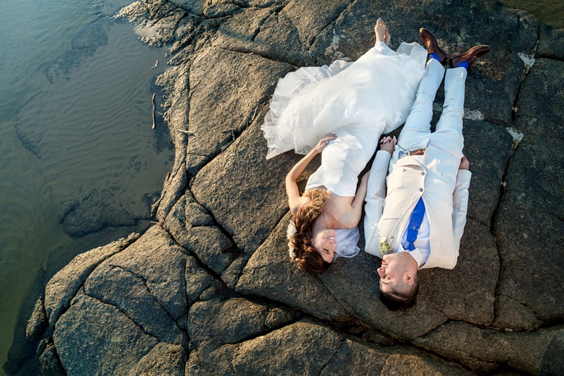 Bride and groom lying on a rock in the ocean at Estuary Hotel, Port Edward