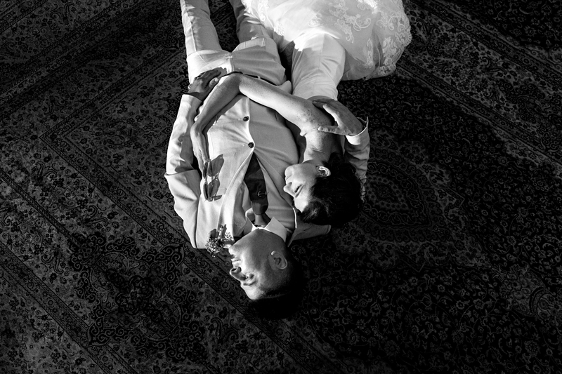 Bride and groom lying on a Persian rug at estuary Hotel, Port Edward