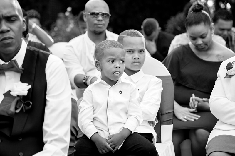 Black and white photograph, child sticking out his tongue during ceremony at Valverde Eco Hotel.