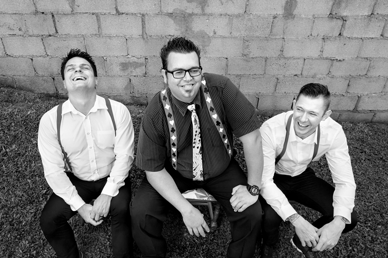 Groom and groomsmen laughing before Alice in Wonderland themed wedding