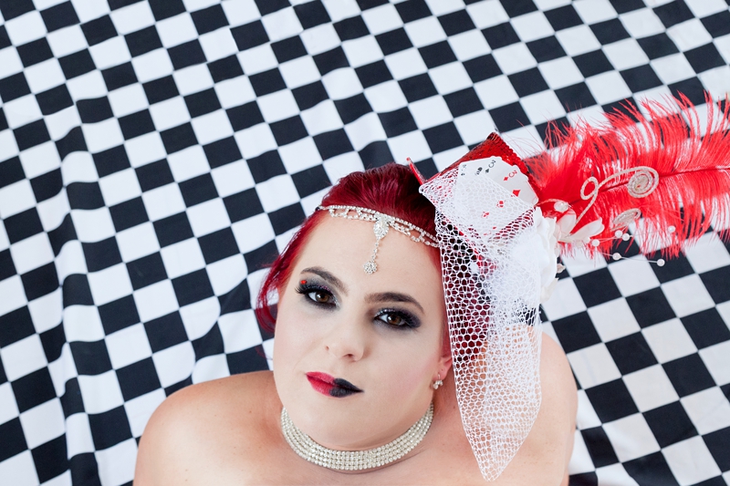 Alice in Wonderland bride wearing black and red makeup, while lying on a black and white floor.