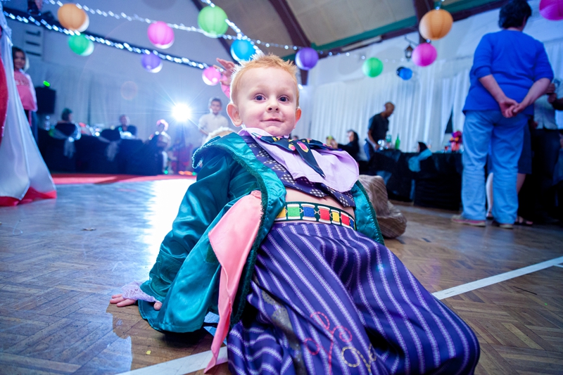 Small boy on his knees, on the dance floor during Alice in Wonderland themed wedding.