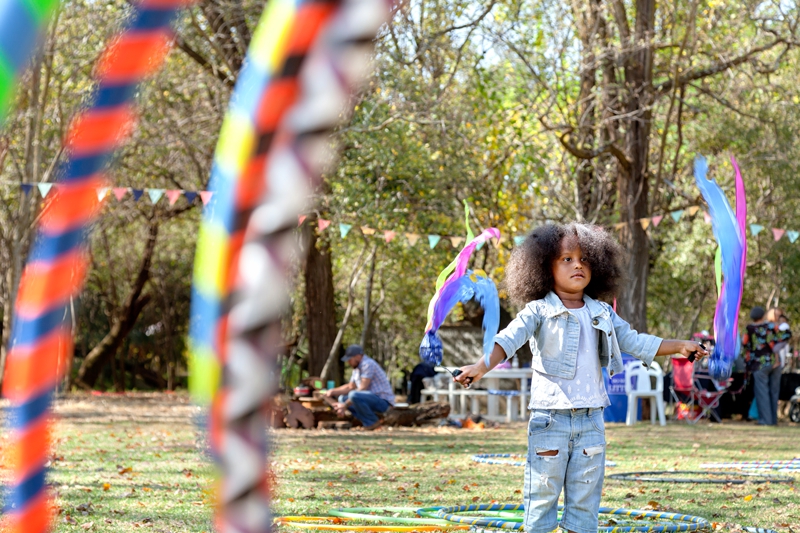 Child with natural afro, swinging colourful ribbons during Hippie Fest,at the Forest Venue.
