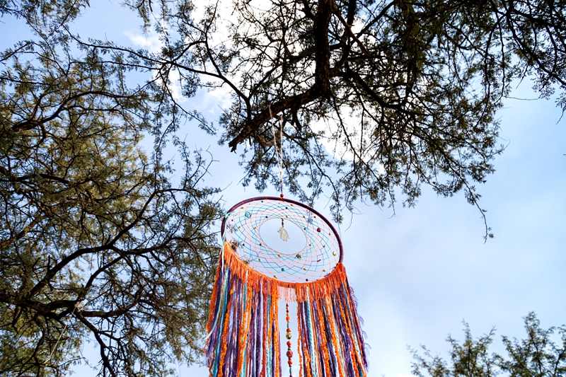 Colourful Hamsa hand dreamcatcher made by GentleTrends Collections, hanging from a tree during Hippie Fest, at the Forest Venue.