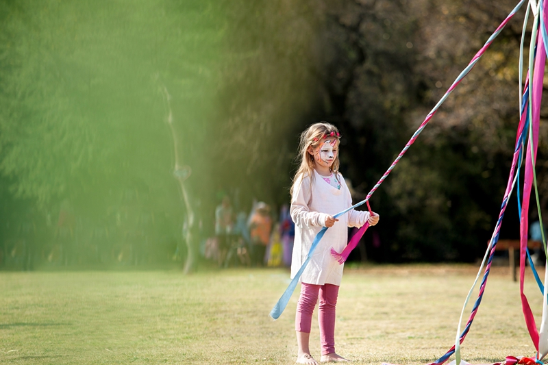 Girl with painted face, braiding Maypole ribbons during Hippie Fest, at the Forest Venue.