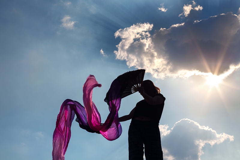 Flow artist from Shantizzles_hoops  performing with purple Chinese dance fan ribbons, during Hippie Fest, at the Forest Venue.