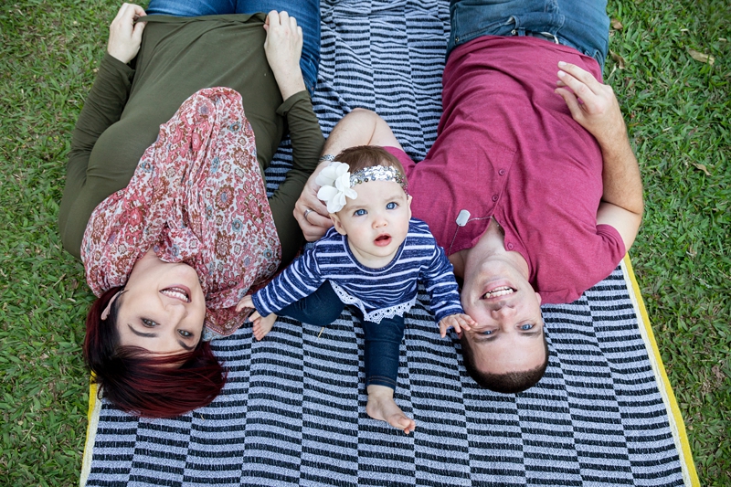 Parents lying on striped blanket with toddler, wearing a flower sequin headband at Japanese Gardens, Pinetown.