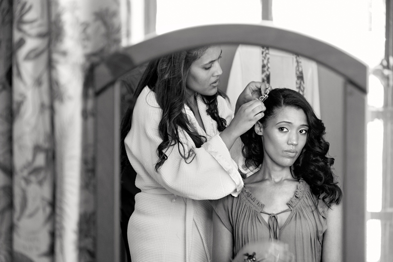 Bride's reflection in mirror, while having her hair clip put on.