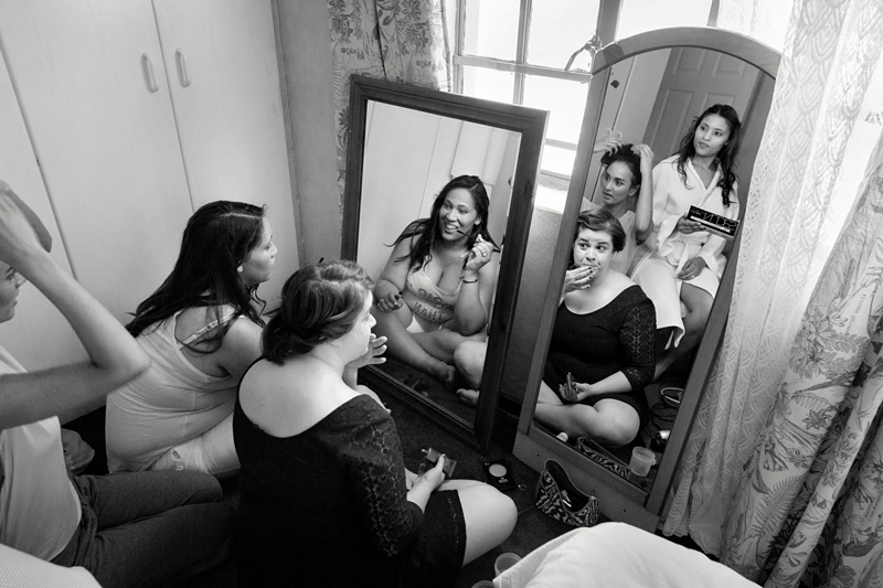 Bridesmaids reflection in mirror, while doing hair and makeup.