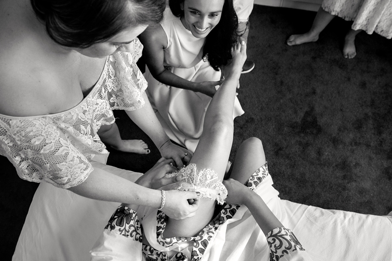 Bridesmaids putting on the brides garter.