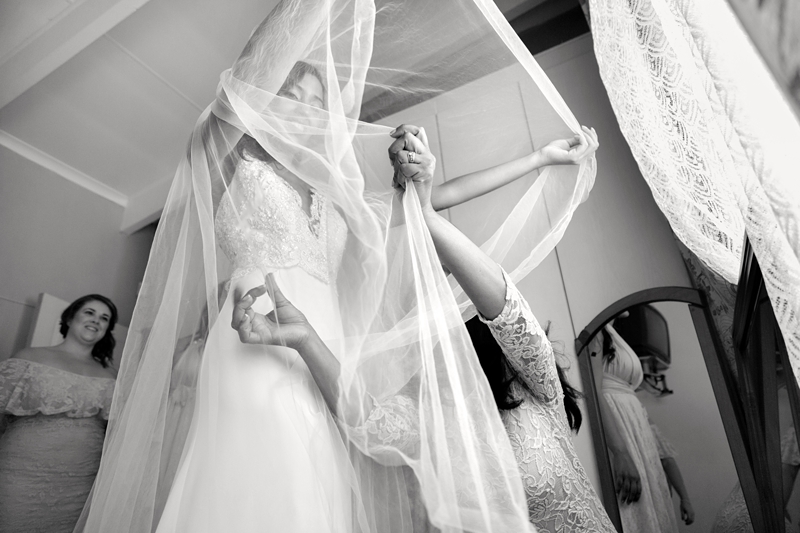 Mother of the bride helping the bride with the long veil.