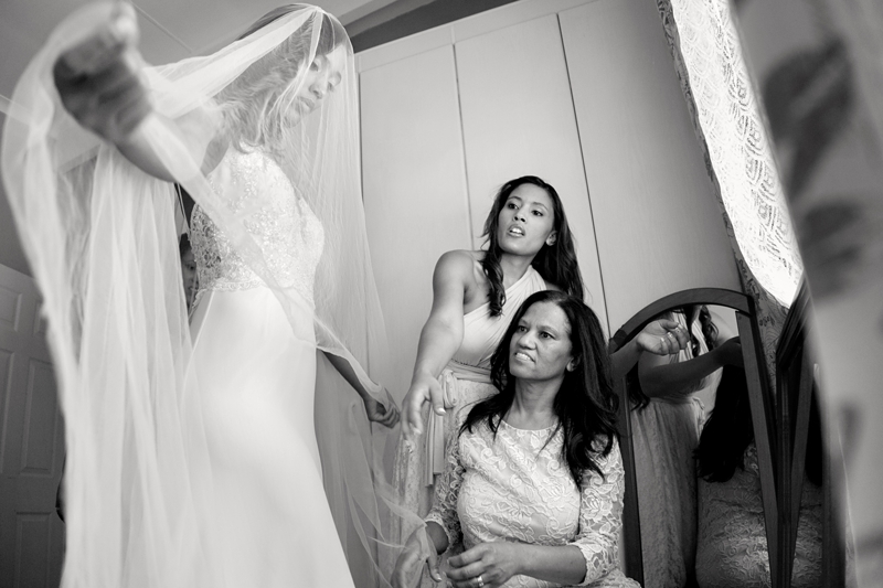 Bride wearing long white lace wedding dress, fixing her veil.