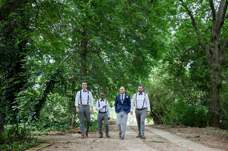 Groom and groomsmen walking under canopy of trees at Leafy Green Cafe.