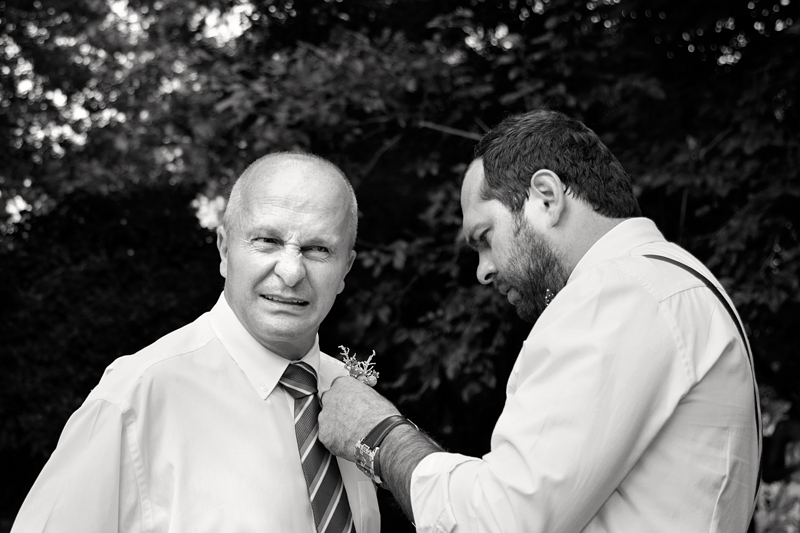 Man pulling funny face while having his boutonnière fastened.