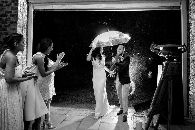 Bride and groom running with an umbrella to the reception hall at Leafy Green Cafe.