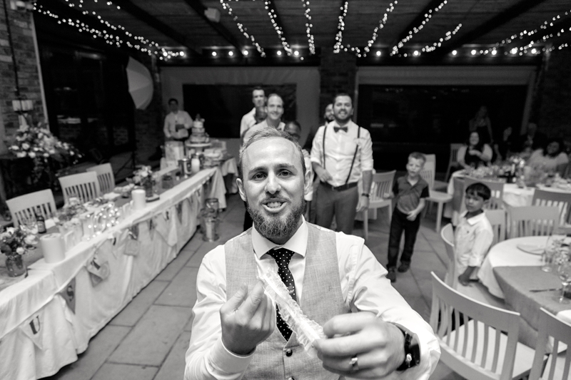 Groom about to throw garter at wedding reception, at Leafy Green Cafe.