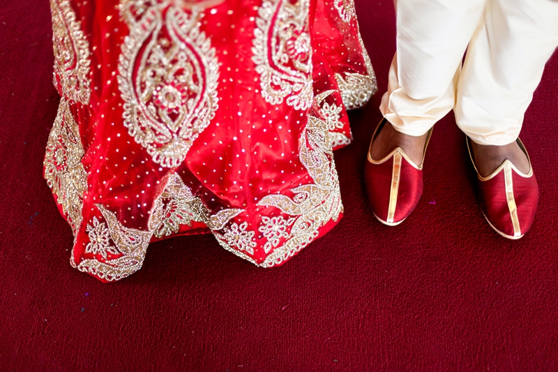 Red wedding sari and red groom shoes on red carpet at Shree Radhe Shyam Mandir