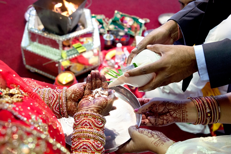 Bride's hands with Mhendi and shiny bangles during Hindu ceremony at Shree Radhe Shyam Mandir.