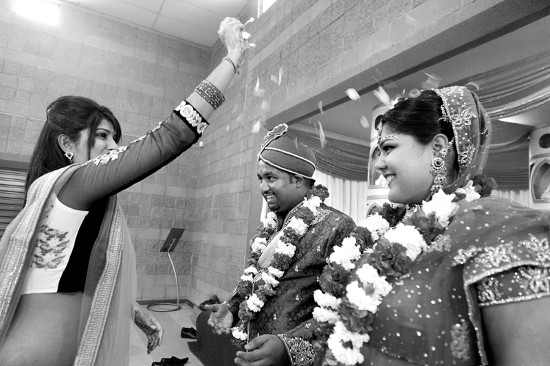 Bride and groom having rose petals thrown over them during Hindu ceremony at Shree Radhe Shyam Mandir.