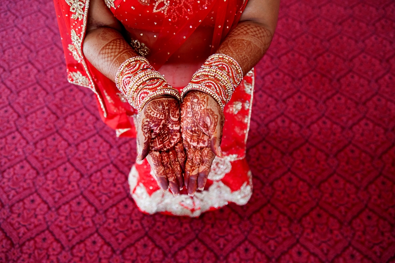Hindu Bridal mhendi, with red and gold sari and bangles, standing on red carpet at Shree Radhe Shyam Mandir.