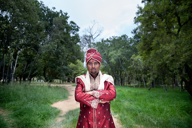 Hindu groom wearing traditional red wedding outfit at Shree Radhe Shyam Mandir.