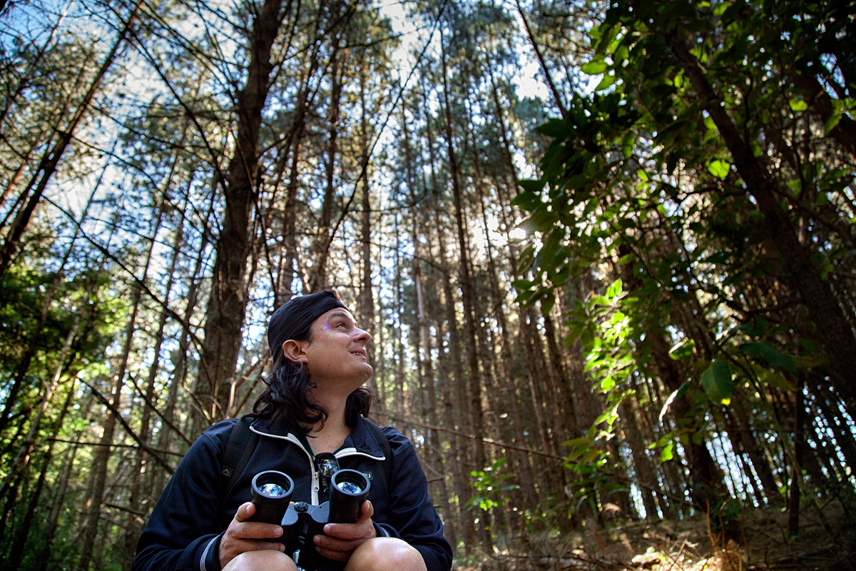Man with binoculars sitting in a forest